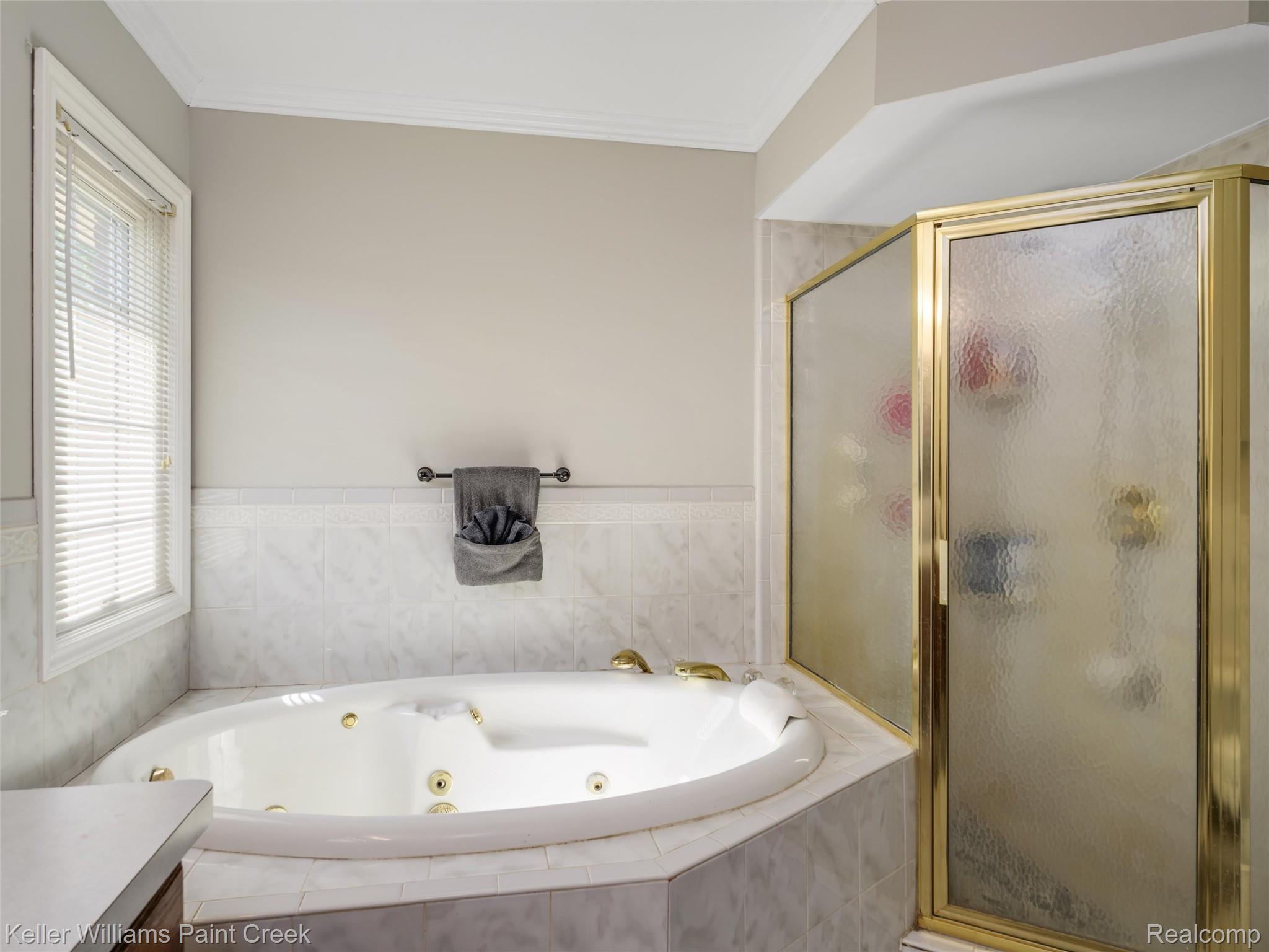 5813 36 Mile Road Romeo, MI 48065 - Photo 29 of 81 Bathroom featuring a corner jetted tub, a separate shower with a frosted glass enclosure and gold-tone framing, and white tiled walls