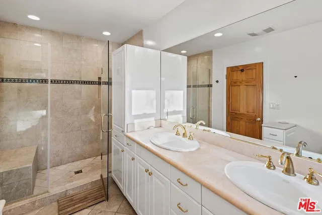 a bathroom with a double vanity sink and mirror with shower