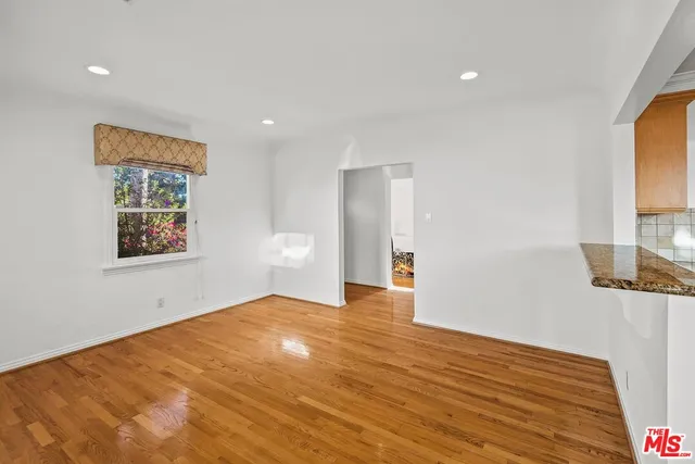 a view of an empty room with wooden floor and a window