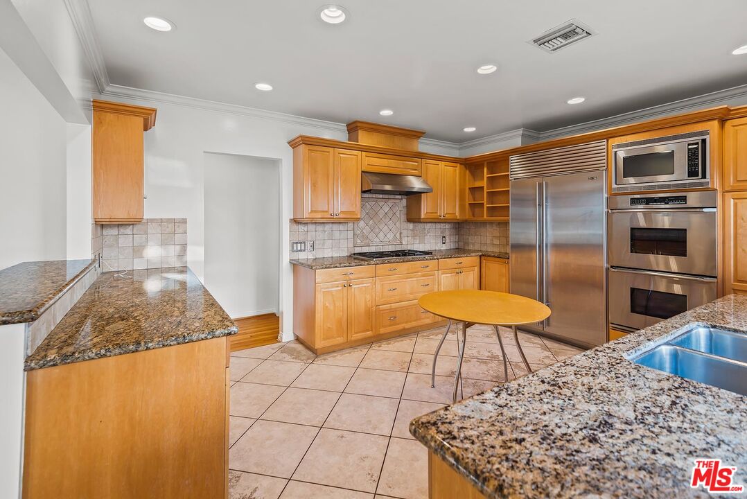 10497 Kinnard Avenue Los Angeles, CA 90024 - Photo 8 of 19 a kitchen with stainless steel appliances kitchen island granite countertop a refrigerator and a stove top oven