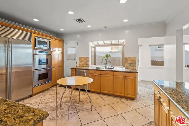 a kitchen with stainless steel appliances granite countertop a sink and a refrigerator