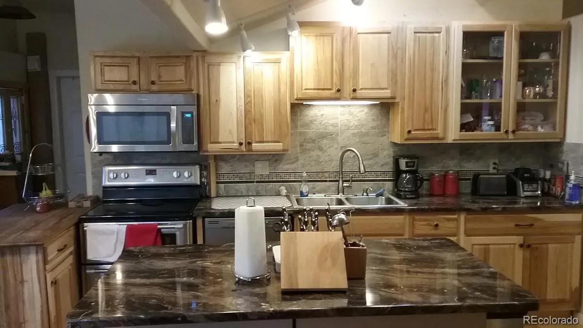 5091 South Olive Road Evergreen, CO 80439 - Photo 2 of 23 a kitchen with stainless steel appliances granite countertop a stove a sink and a microwave