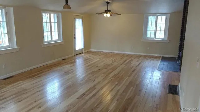 an empty room with wooden floor and windows