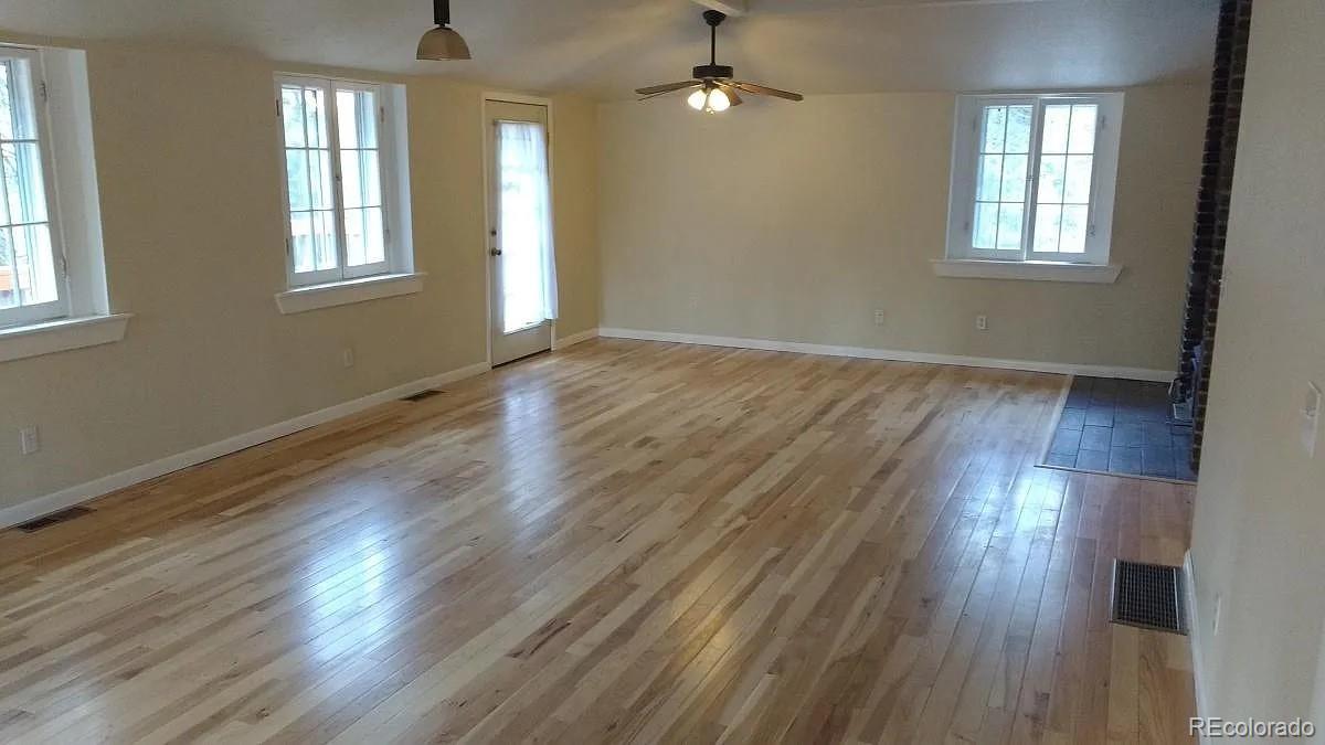 5091 South Olive Road Evergreen, CO 80439 - Photo 8 of 23 an empty room with wooden floor and windows