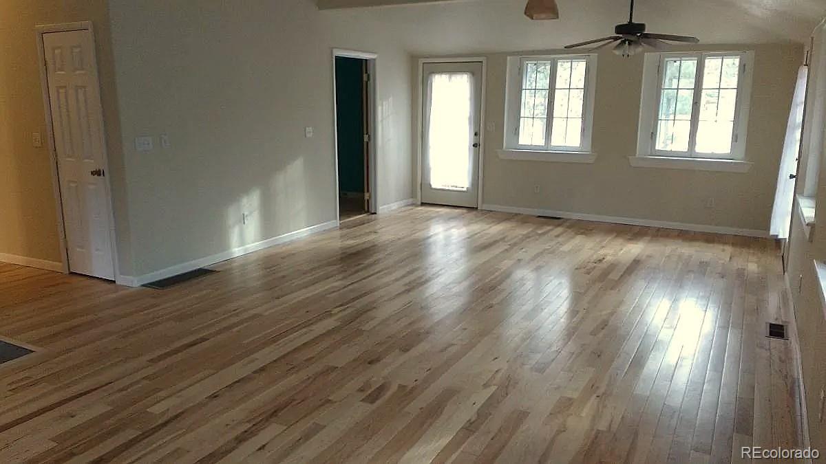 5091 South Olive Road Evergreen, CO 80439 - Photo 9 of 23 an empty room with wooden floor and windows