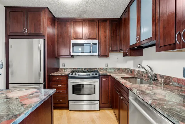a kitchen with granite countertop stainless steel appliances and wooden cabinets