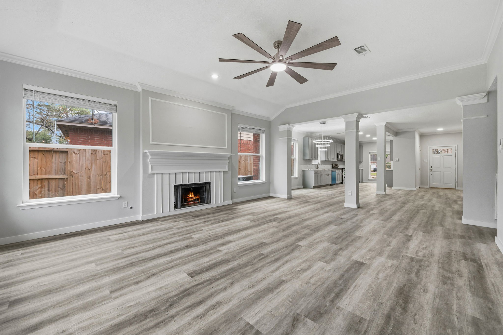 5411 Shady Maple Drive Houston, TX 77339 - Photo 14 of 28 This spacious open-concept living area features modern flooring, a cozy fireplace, ample natural light from large windows, and a ceiling fan. The room flows seamlessly into the kitchen and dining areas, offering a perfect setup for entertaining.