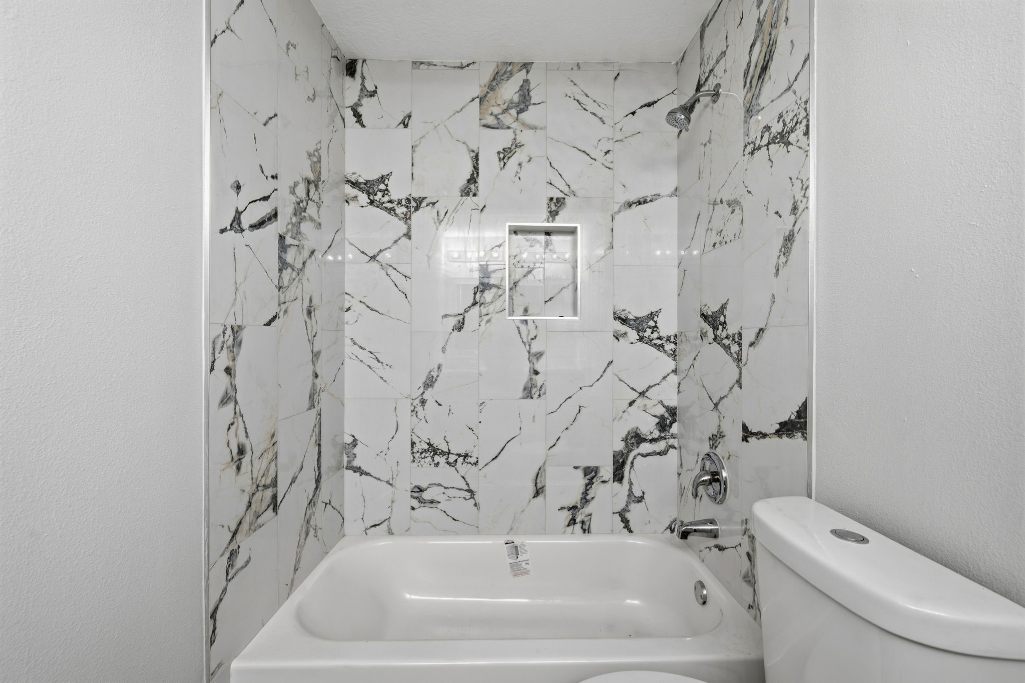 5411 Shady Maple Drive Houston, TX 77339 - Photo 19 of 28 This bathroom features a modern tub and shower combination with elegant marble-style tile, providing a clean and sophisticated look.