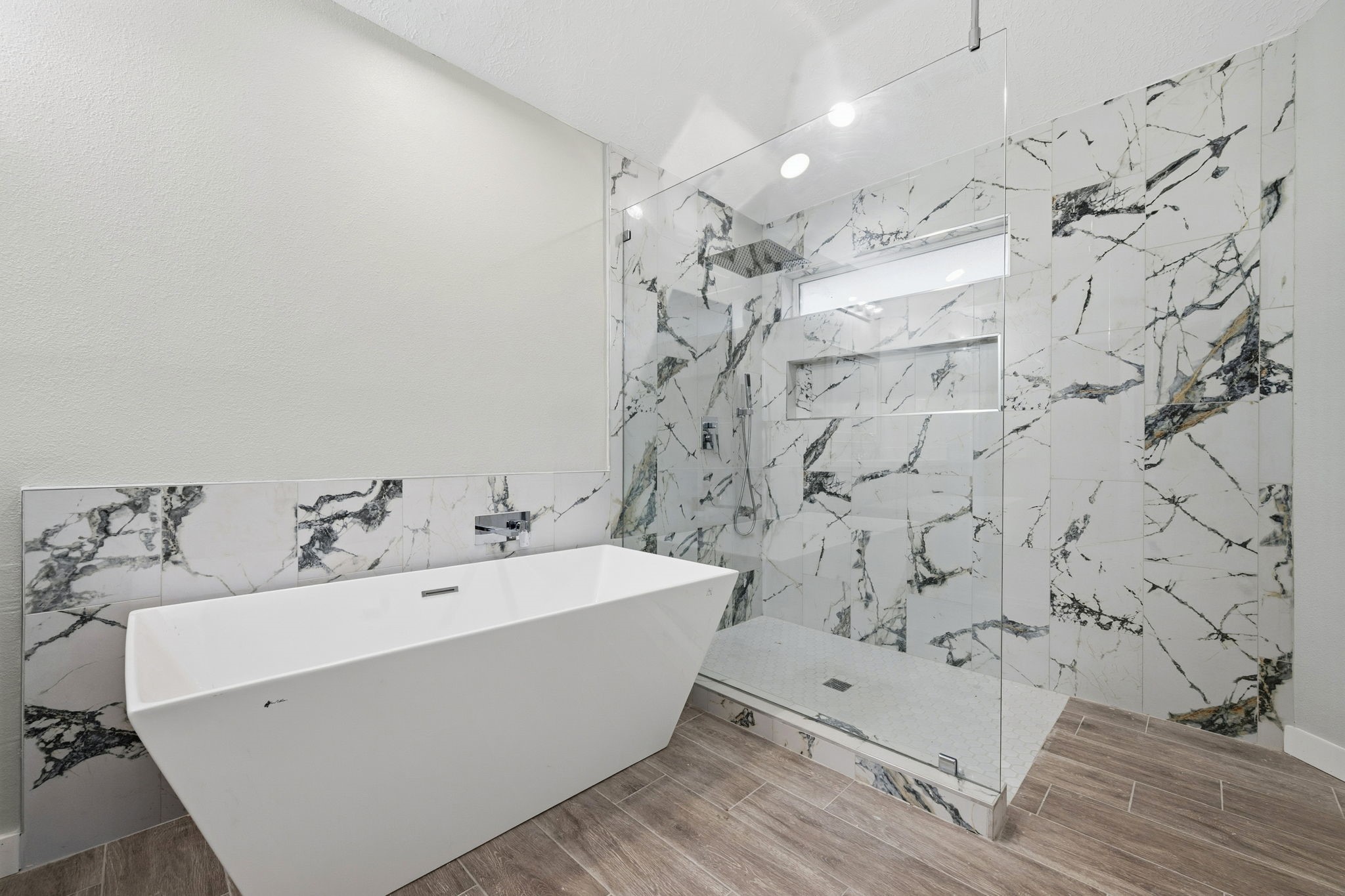 5411 Shady Maple Drive Houston, TX 77339 - Photo 24 of 28 This bathroom features a modern freestanding tub and a spacious glass-enclosed shower with striking marble-patterned tile, creating a luxurious and elegant atmosphere.