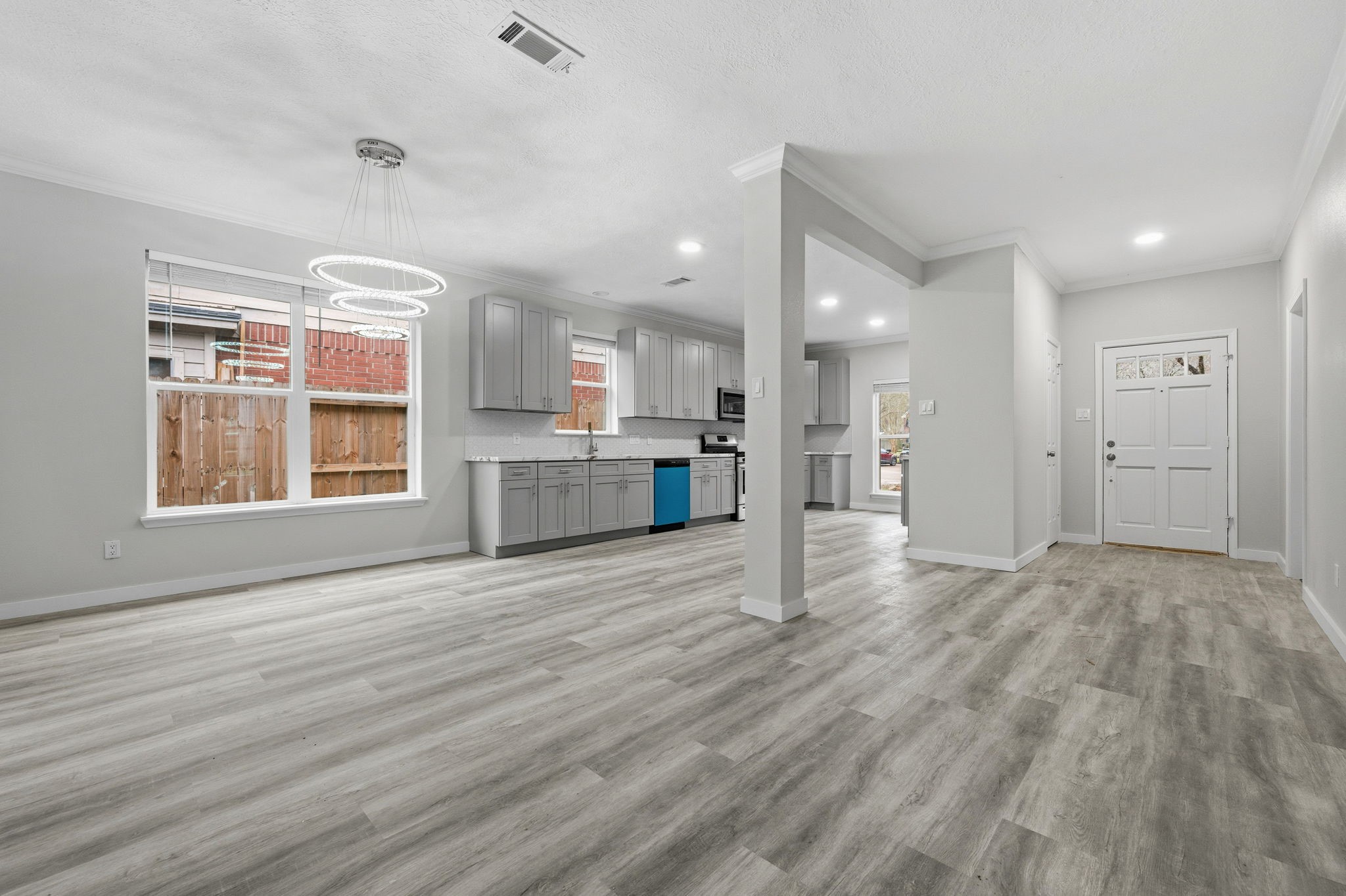 5411 Shady Maple Drive Houston, TX 77339 - Photo 6 of 28 Open-concept living space with light wood flooring and ample natural light. The kitchen features sleek gray cabinets, stainless steel appliances, and contemporary lighting. The layout is spacious, ideal for both entertaining and everyday living.