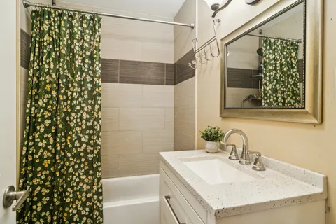 a bathroom with a granite countertop sink and a shower