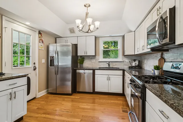 a kitchen with stainless steel appliances granite countertop a stove a sink dishwasher a refrigerator and a stove with wooden floor