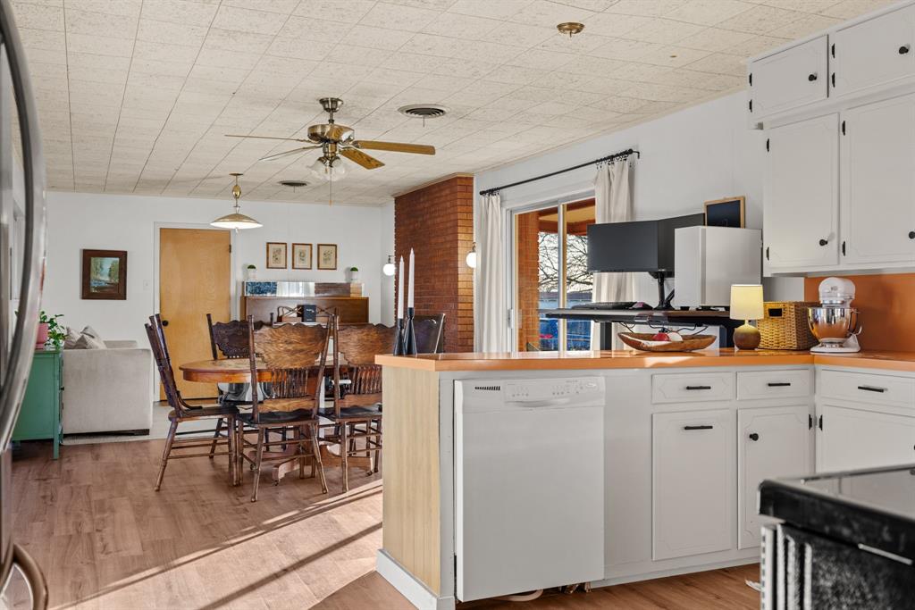910 South Harrison Street West, TX 76691 - Photo 13 of 39 a kitchen with stainless steel appliances granite countertop a stove top oven a refrigerator a dining table and chairs with wooden floor