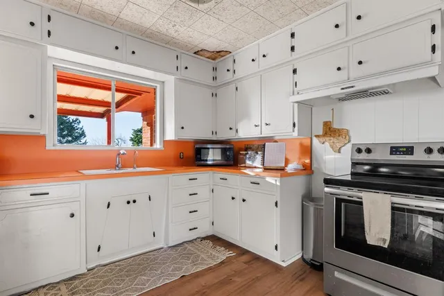 a kitchen with granite countertop white cabinets and window