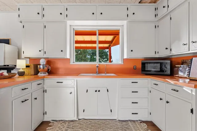 a kitchen with white cabinets and window