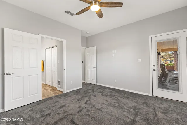 a view of an empty room with closet and a ceiling fan