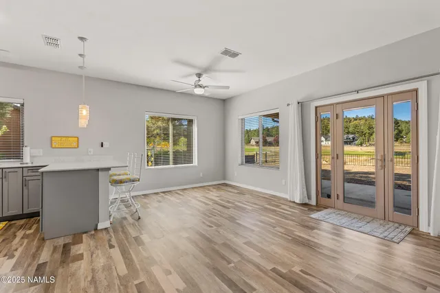 a view of an empty room with window and wooden floor