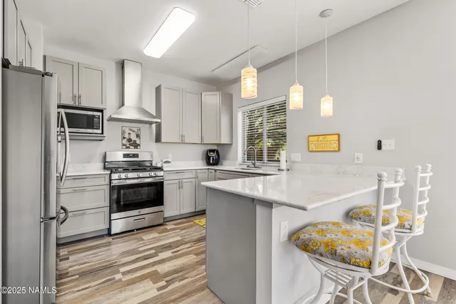 a kitchen with stainless steel appliances a stove a sink refrigerator and white cabinets with wooden floor