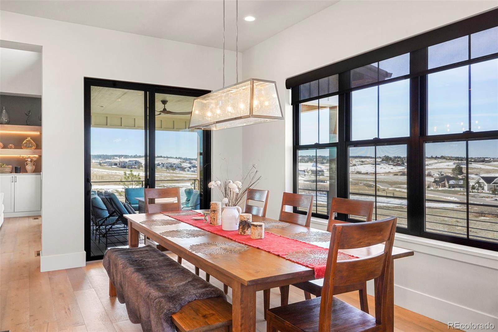 10621 Lone Fox Road Franktown, CO 80116 - Photo 18 of 50 a dining room with furniture a chandelier and wooden floor