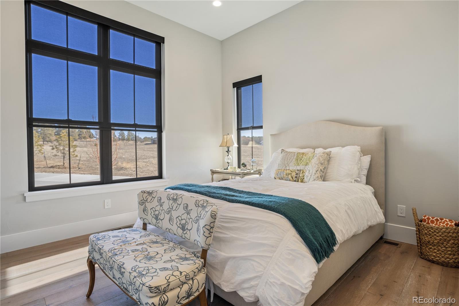 10621 Lone Fox Road Franktown, CO 80116 - Photo 33 of 50 a large bedroom with a bed and wooden floor