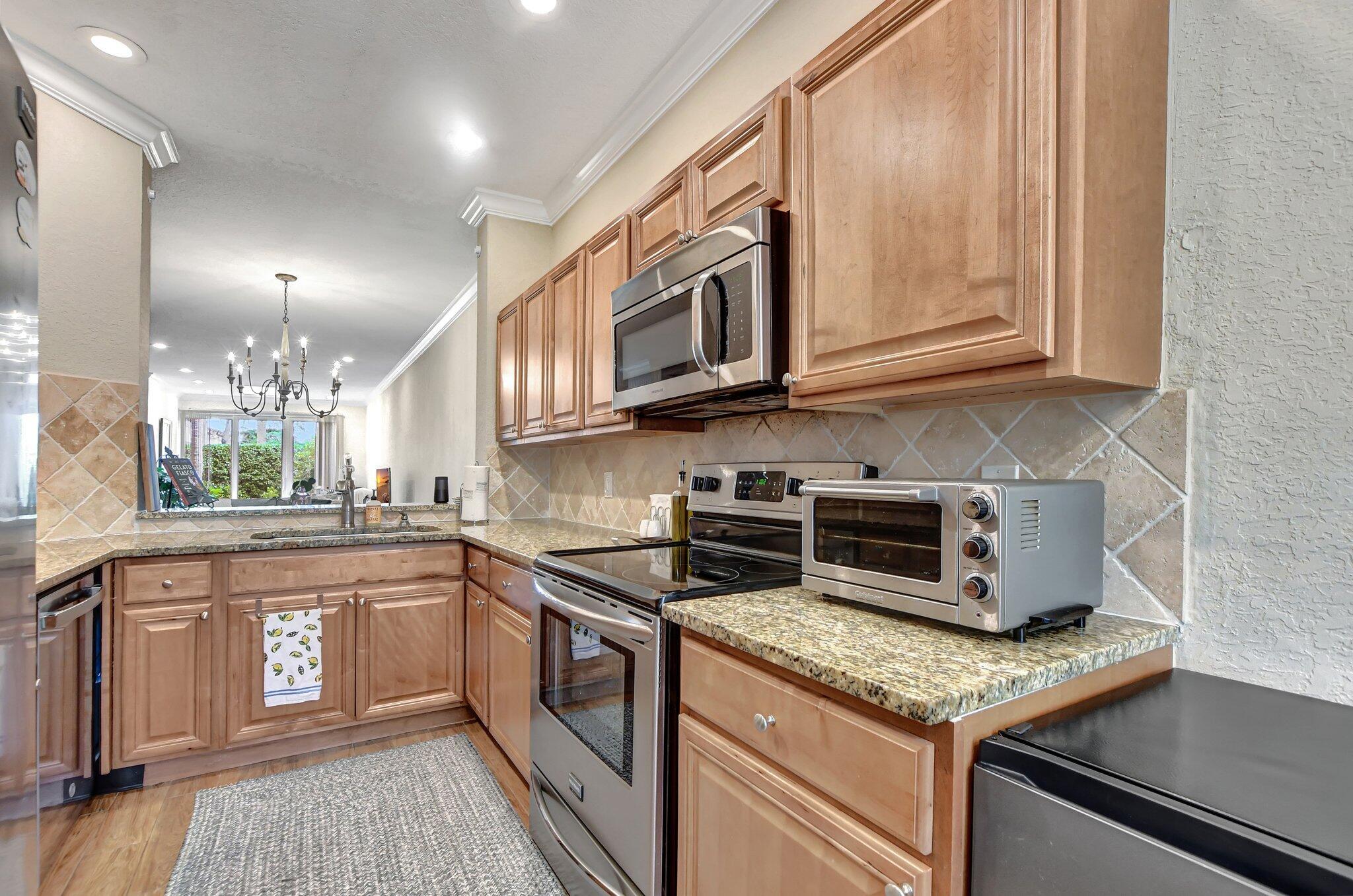 6682 Via Regina Boca Raton, FL 33433 - Photo 7 of 46 a kitchen with stainless steel appliances granite countertop a stove a sink and a microwave