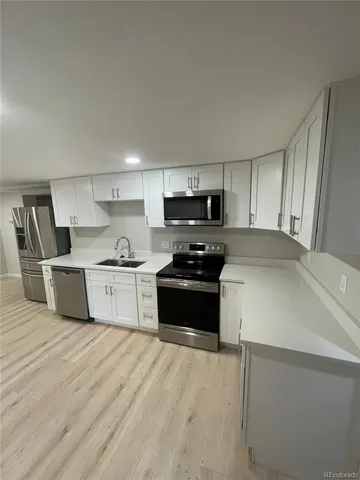 a kitchen with stainless steel appliances granite countertop a sink a stove top oven and white cabinets
