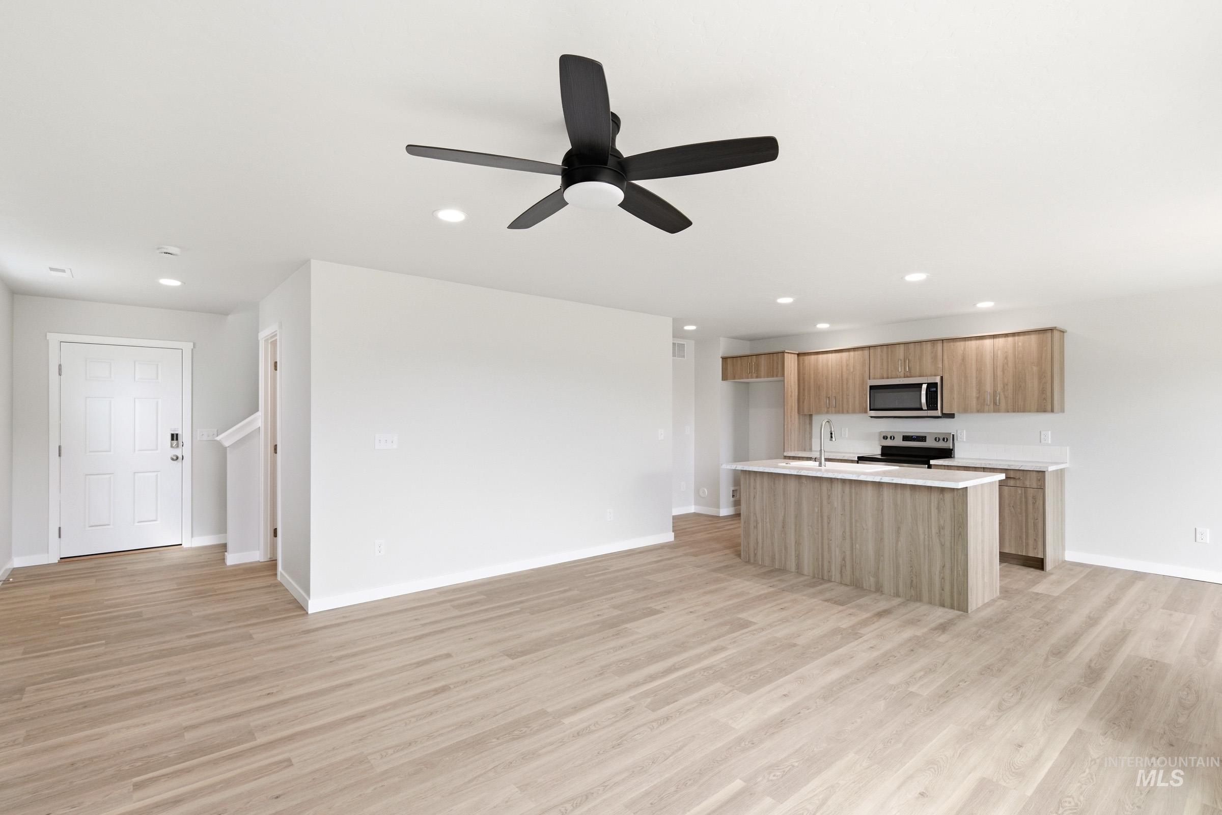 2446 West Fallon Loop Nampa, ID 83651 - Photo 19 of 19 Kitchen with open floor plan, ceiling fan, a kitchen island with sink, stainless steel appliances, and light wood finished floors