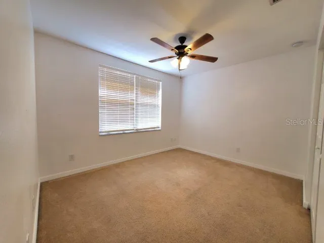 an empty room with a window and a fan