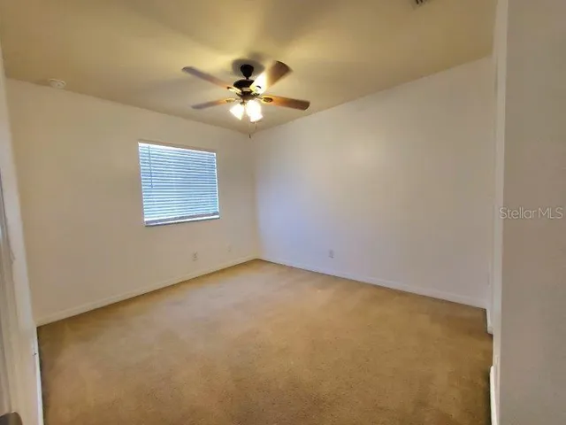 an empty room with a window and a fan