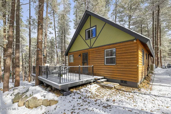 a view of a small house with a small yard and wooden deck