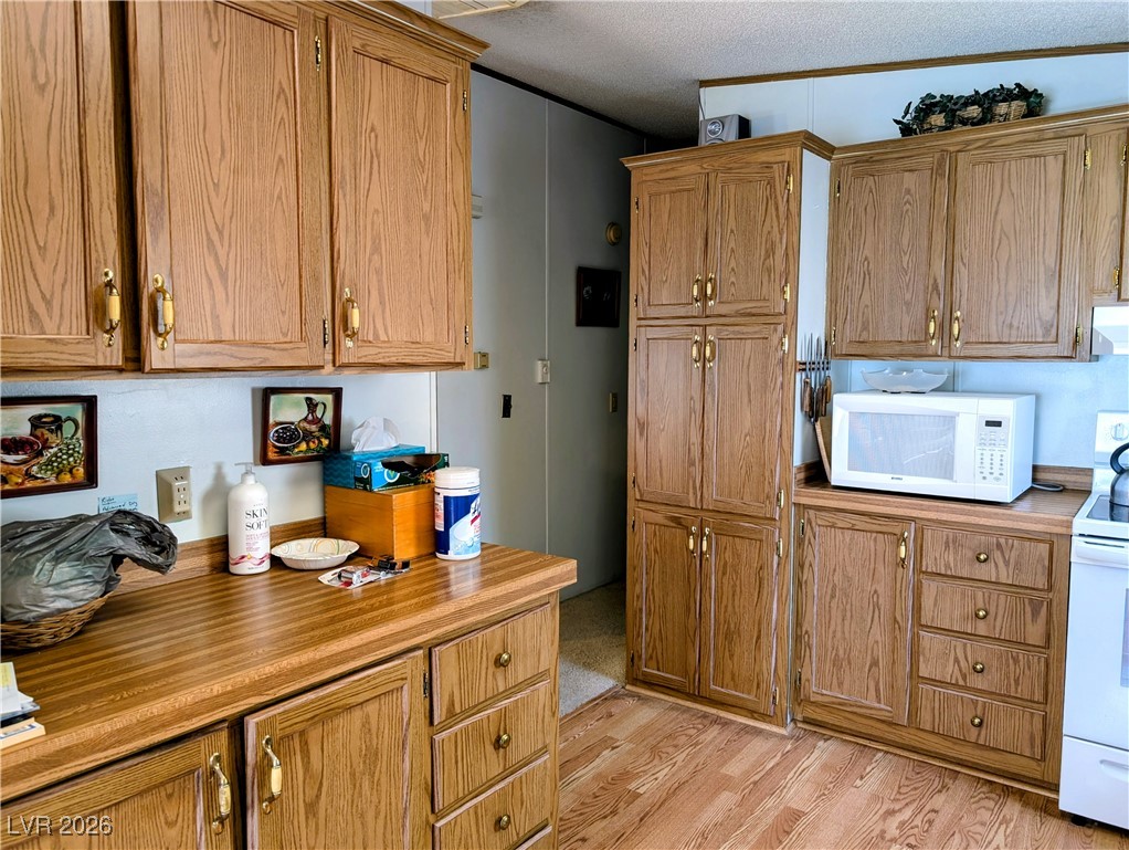50 North 2nd Street Panaca, NV 89042 - Photo 14 of 35 Kitchen featuring white appliances, light wood finished floors, a textured ceiling, exhaust hood, and light countertops