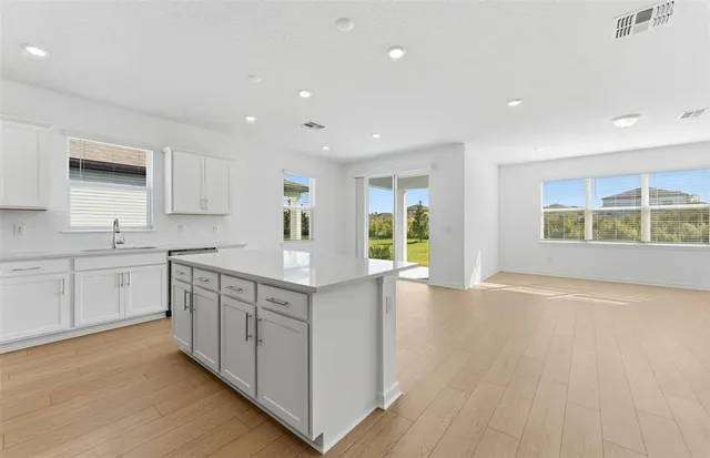 a kitchen with stainless steel appliances granite countertop a stove a sink and white cabinets with wooden floor
