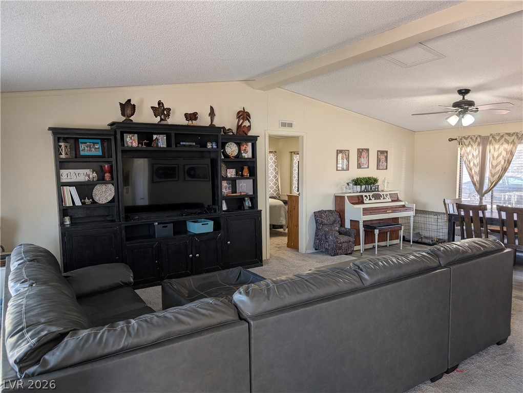 320 6th Street Panaca, NV 89042 - Photo 5 of 31 Carpeted living room featuring a ceiling fan, a textured ceiling, and beamed ceiling