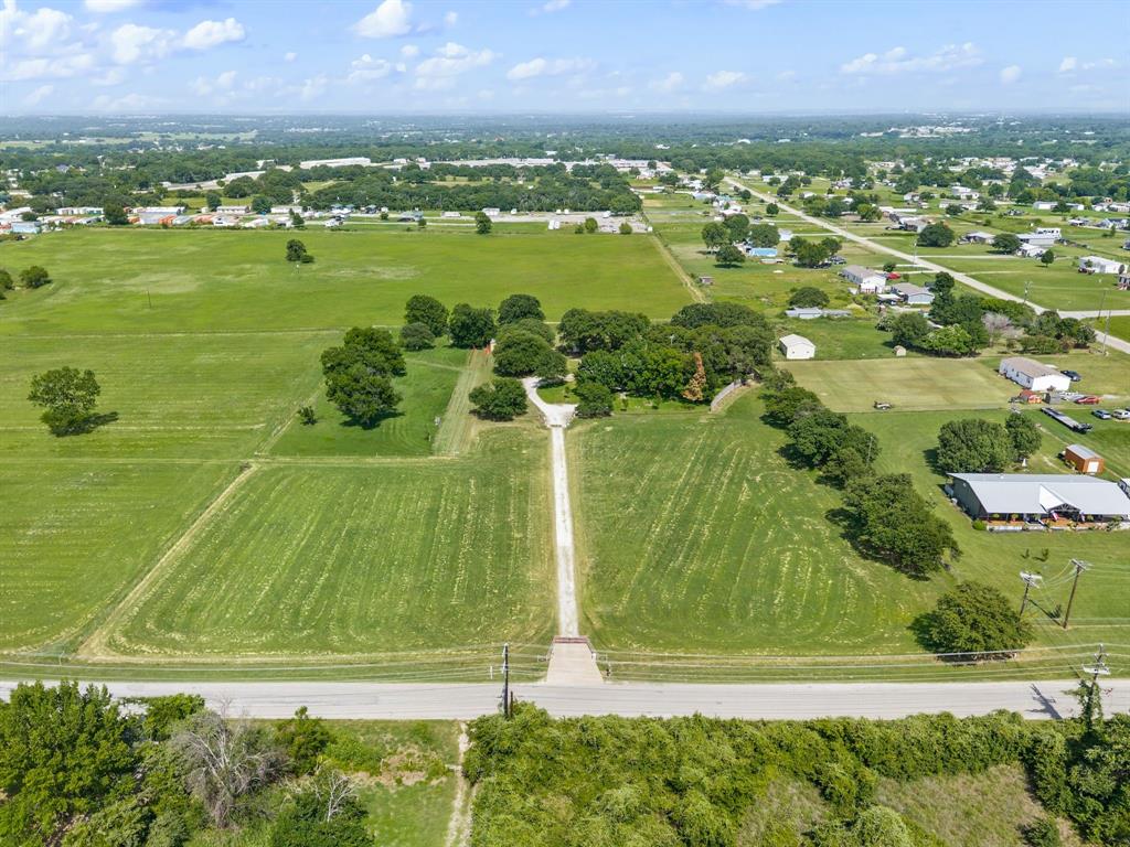 515 New Highland Road Springtown, TX 76082 - Photo 6 of 38 Expansive green fields featuring a long, unpaved driveway leading to a cluster of mature trees