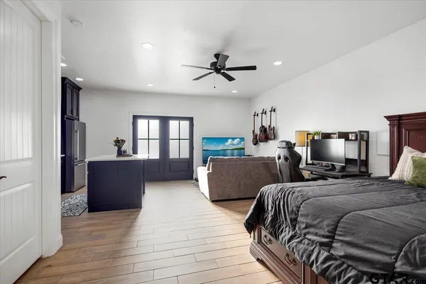 a bedroom with bed a flat tv screen and a dresser