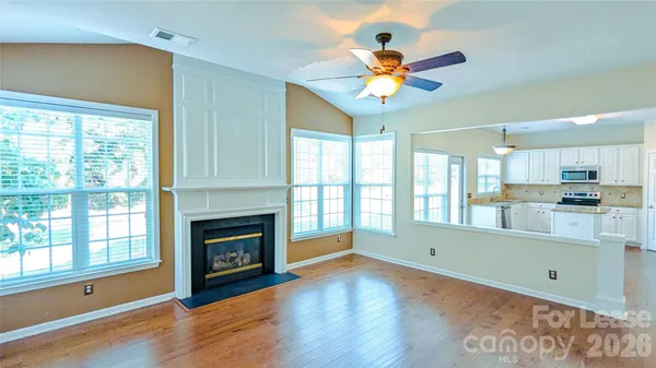 a view of an empty room with a window and wooden floor