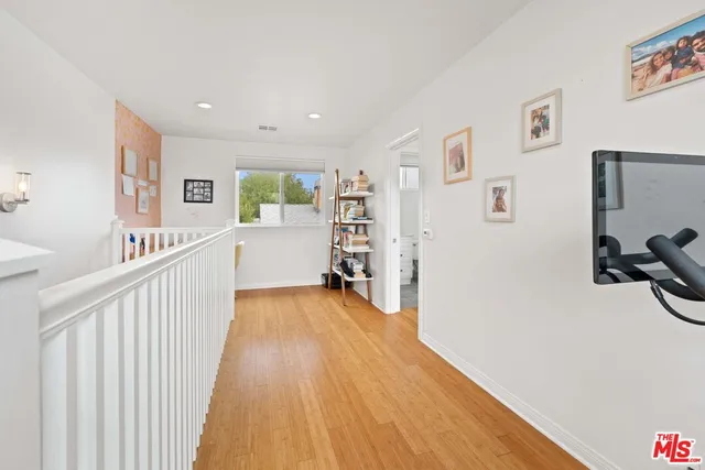 a view of a hallway with workspace and wooden floor