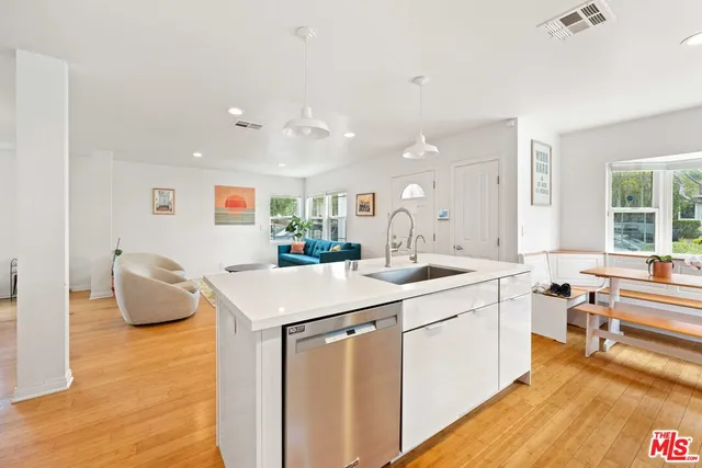 a large white kitchen with a sink and dishwasher a stove with wooden floor
