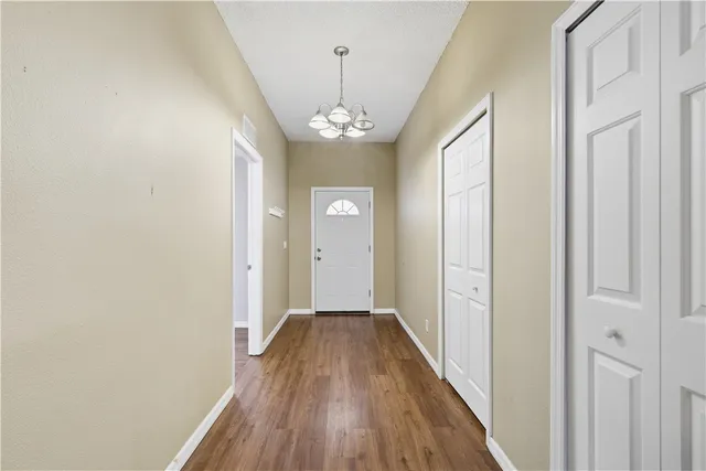a view of a hallway with wooden floor and chandelier