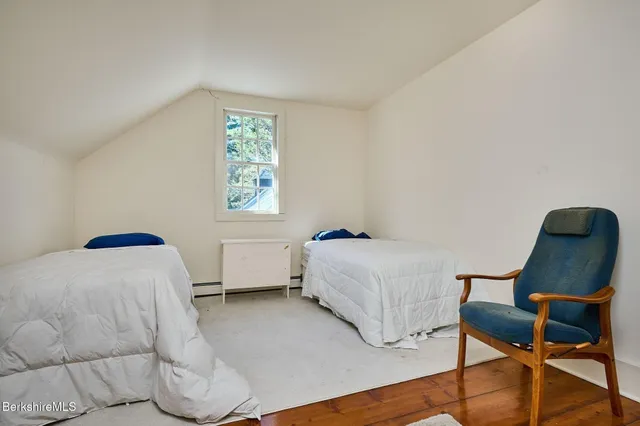 a bedroom with a bed a chair and painting on the wall