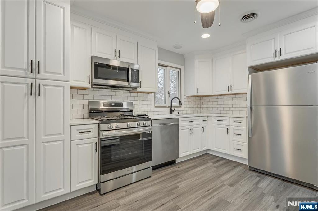 35 Field Road, Unit 2 Maplewood, NJ 07040 - Photo 7 of 13 a kitchen with white cabinets stainless steel appliances and wooden floors