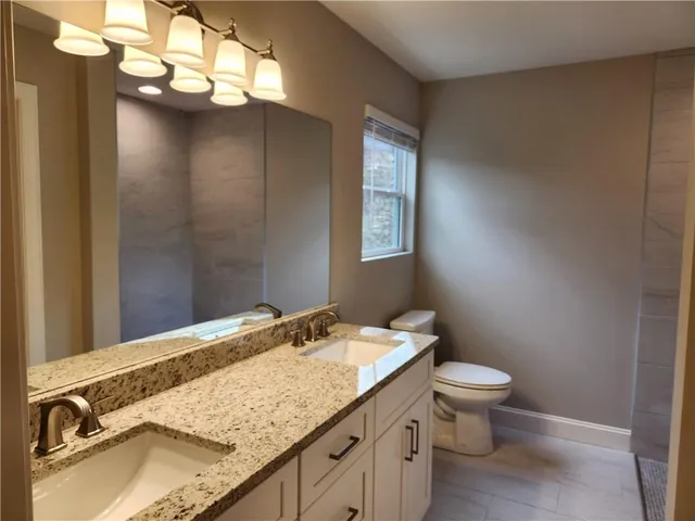 a bathroom with a granite countertop sink a toilet and a mirror