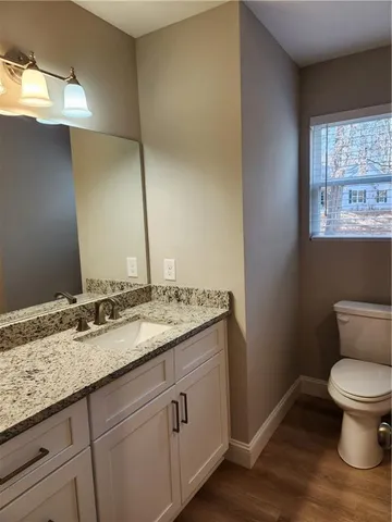 a bathroom with a granite countertop toilet sink and mirror