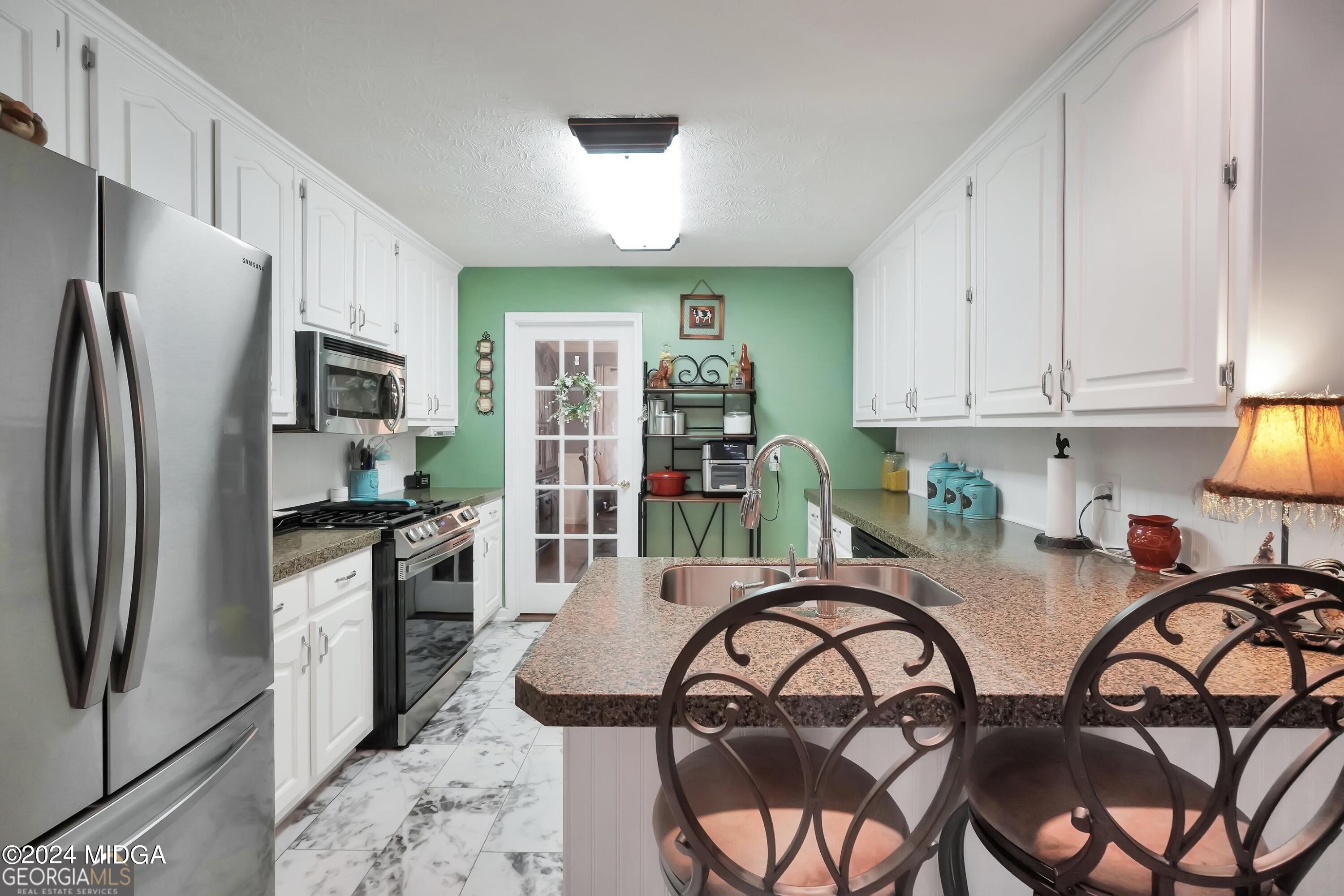 208 Brown Branch Road Locust Grove, GA 30248 - Photo 22 of 44 a kitchen with stainless steel appliances granite countertop a refrigerator a stove a sink a dining table and chairs with wooden floor