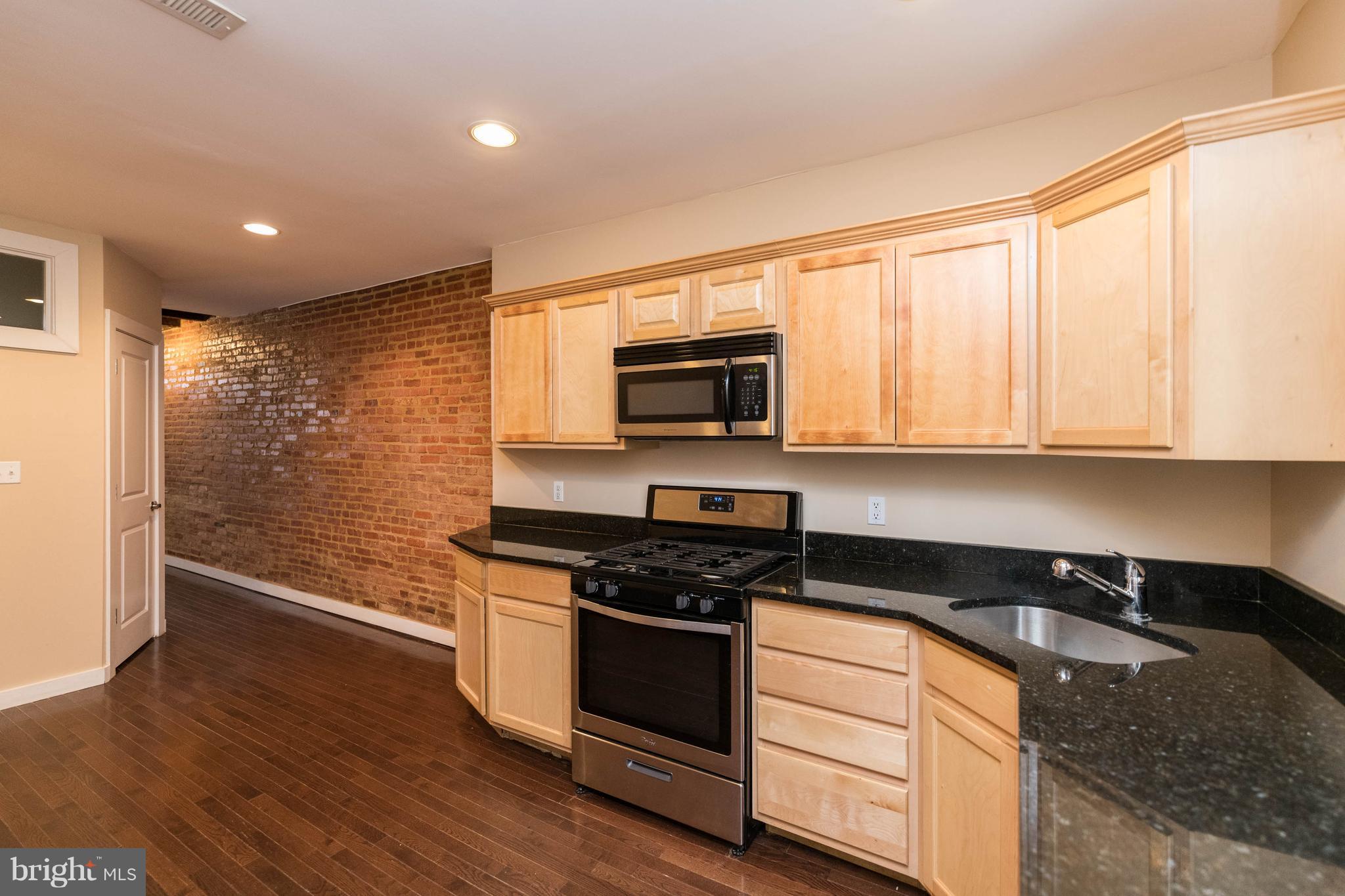 314 West 28th Street Baltimore, MD 21211 - Photo 6 of 27 a kitchen with granite countertop stainless steel appliances a stove top oven and wooden floor