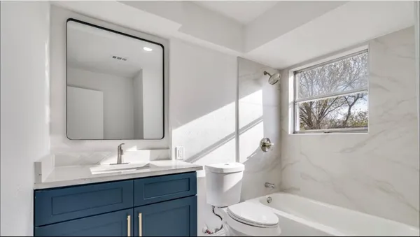 a bathroom with a sink a toilet a mirror a vanity and bathtub