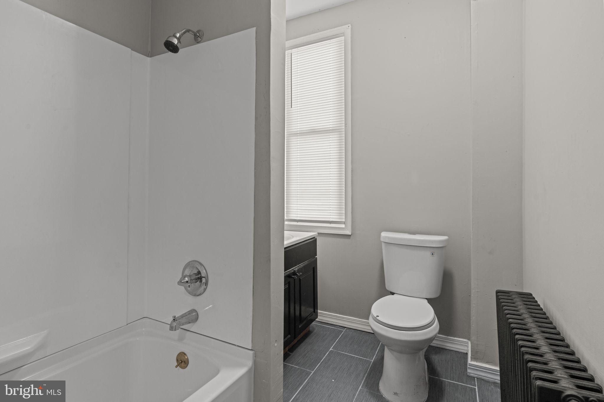 1901 East Venango Street Philadelphia, PA 19134 - Photo 20 of 29 a white toilet sitting next to a bath tub