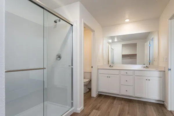 a spacious bathroom with a double vanity sink a mirror and a shower