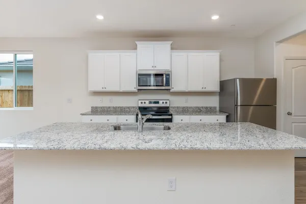 a kitchen with granite countertop a refrigerator and a sink