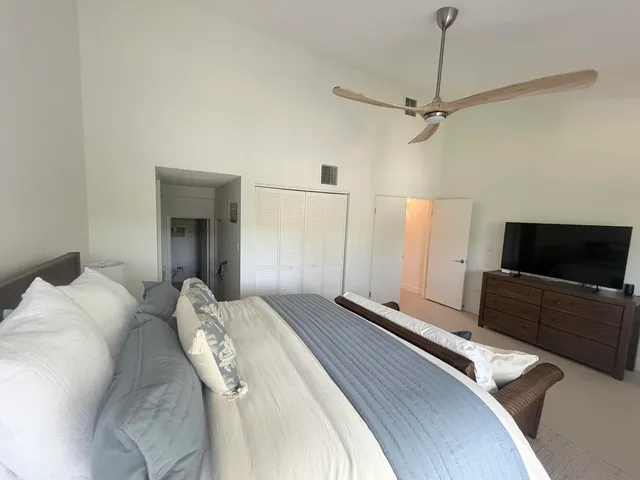 a bedroom with a bed flat screen tv and a large window